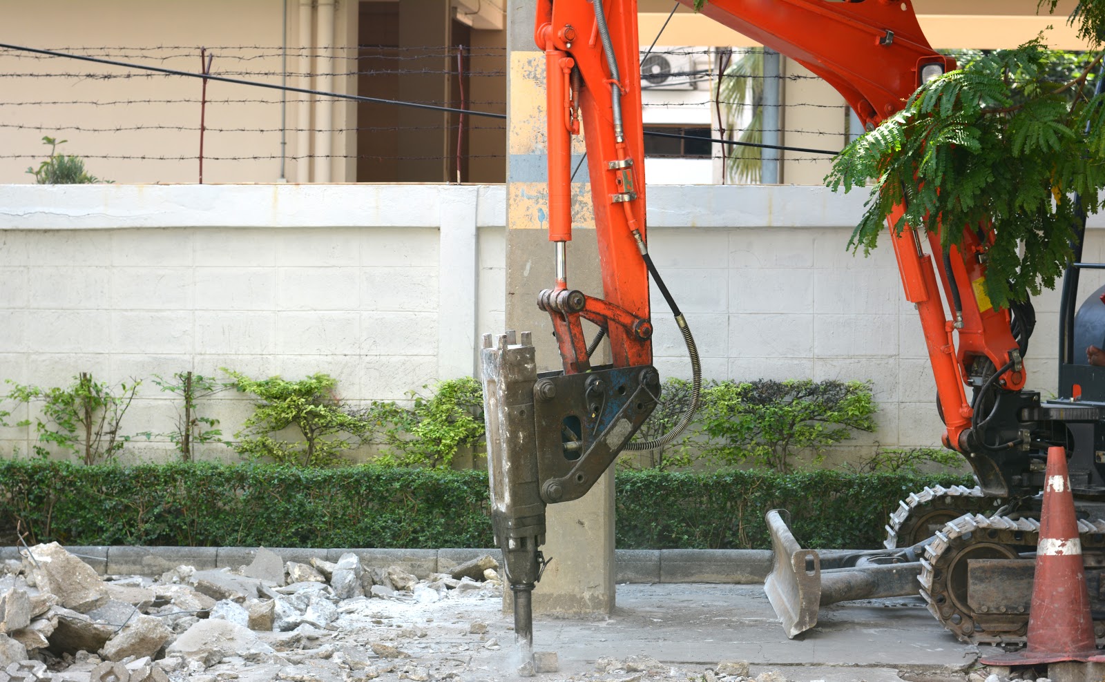 An excavator with hydraulic rock breaker attachment is breaking floor concrete