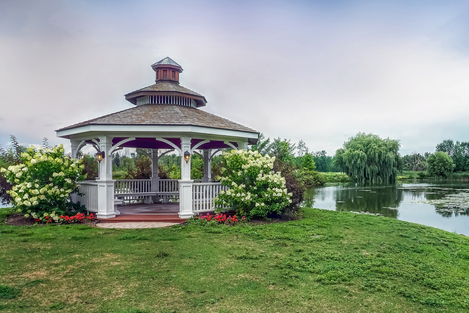 A gazebo in a garden, near a lake