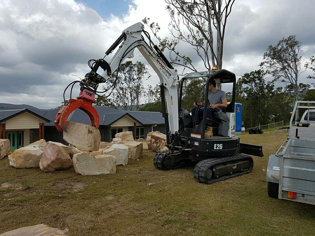 A man is operating an excavator with hydraulic rock grab attachment