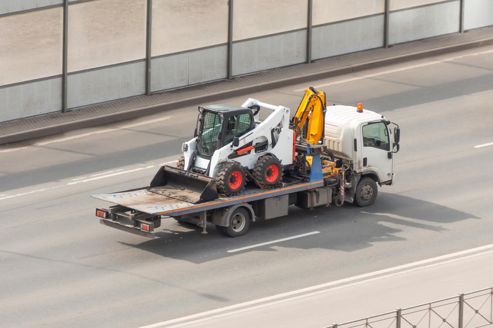 A bobcat loader carrier truck on a road