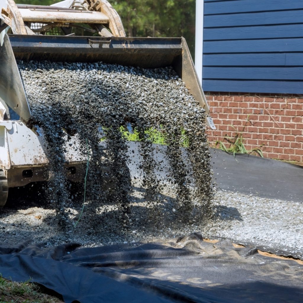 A dry hired loader emptying gravel into a backyard ready for a weekend DIY project.