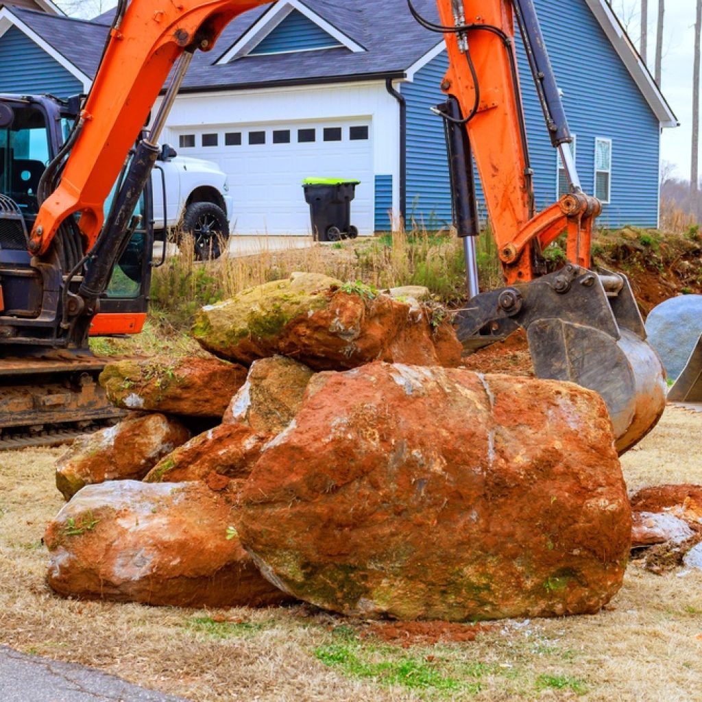 A dry hired excavator picking up rock in a residential area.
