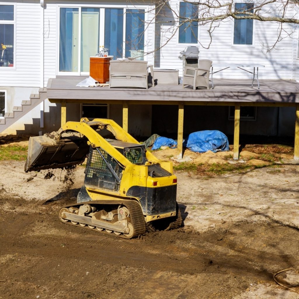 A dry hired loader levelling ground in a backyard. 