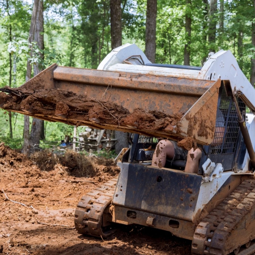 A dry hired loader levelling ground in a backyard. 