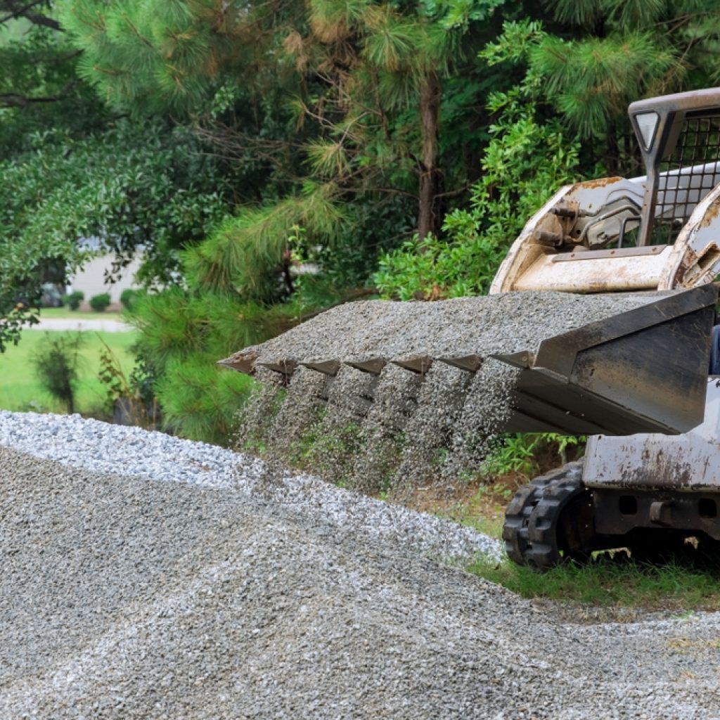 A skid-steer loading moving gravel around a worksite. 
