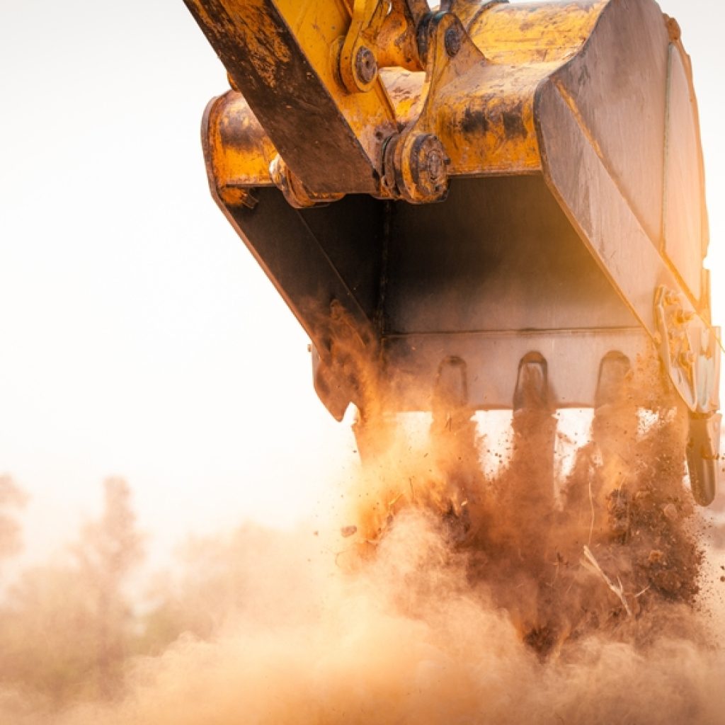 An excavator tipping dirt out of it's bucket displaying earthmoving mistakes to avoid such as having to move the dirt twice.